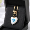 Gold heart keychain with a white and blue evil eye design displayed in a black velvet box