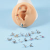 A collection of silver surgical steel demon angel nose studs displayed on a light blue background.