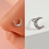 Silver crescent moon nose stud with small diamonds shown on a person's nostril.