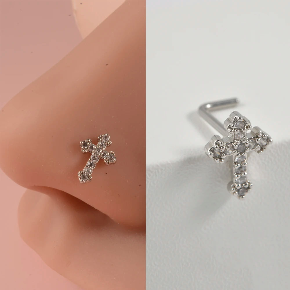 Silver surgical steel demon angel nose studs shown on a pink ear, detailed close-up view.