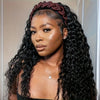 A woman with long, dark curly hair wearing a reddish-brown headband and a delicate necklace.