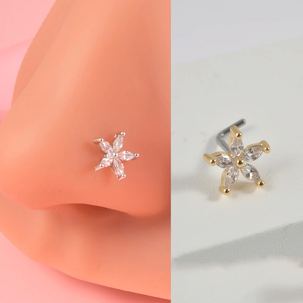 Gold-toned surgical steel demon angel nose studs with a star design shown on a peach-colored skin model.