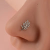 Silver leaf-shaped demon angel nose stud earring on a pink skin model's nostril.
