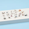 A collection of silver surgical steel demon angel nose studs displayed on a white surface.