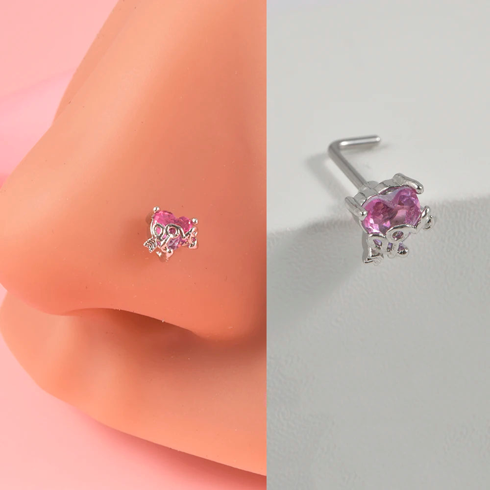 Silver surgical steel demon angel nose studs with pink gemstone on a pink skin model.