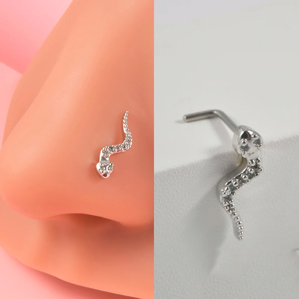 Silver surgical steel demon angel nose stud earring shown next to a peach-colored skin model.