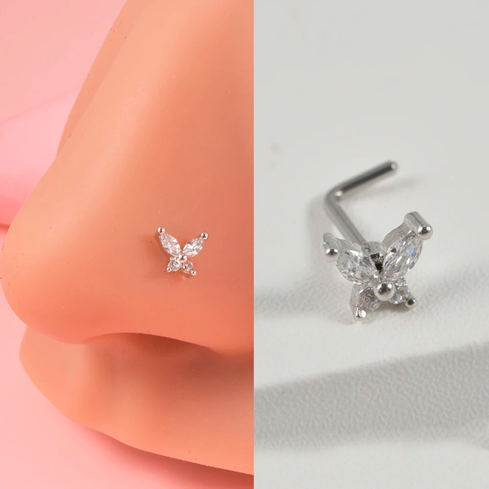 Silver surgical steel demon angel nose stud earrings shown on a pink skin surface