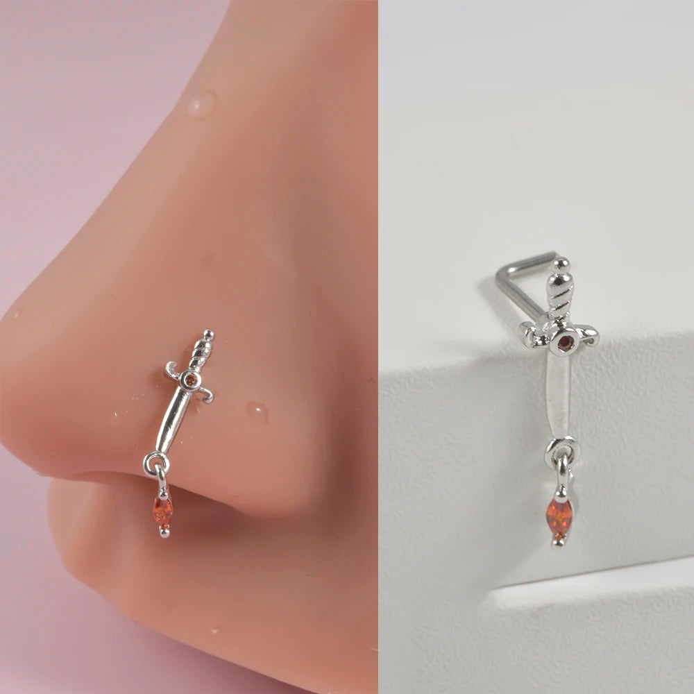Silver surgical steel demon angel nose studs with a dangling orange gemstone.