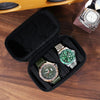 A black leather watch travel case organizer containing three watches and a watch box on a wooden surface.