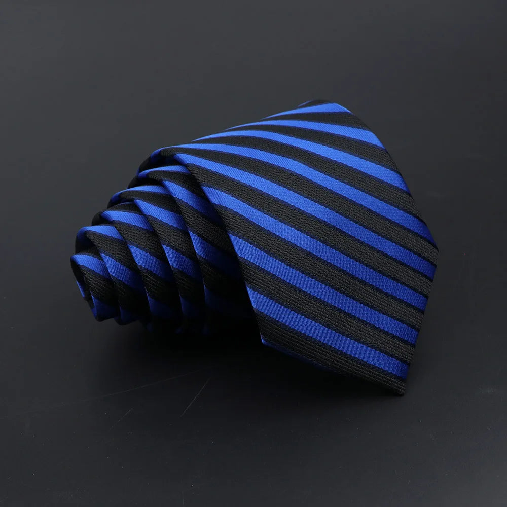 A dark blue and black striped necktie is tightly folded on a dark surface.
