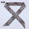 A black and brown leopard print silk headband scarf tied in an 'X' shape.