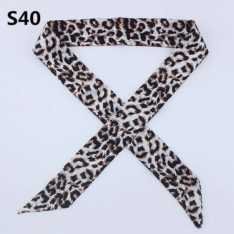 A black and brown leopard print silk headband scarf tied in an 'X' shape.