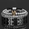 Una pila de pulseras de esmalte de plata y oro con números romanos, mostradas sobre una superficie reflectante.