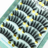A display of black and gray mink false eyelashes arranged in rows on a light green surface.