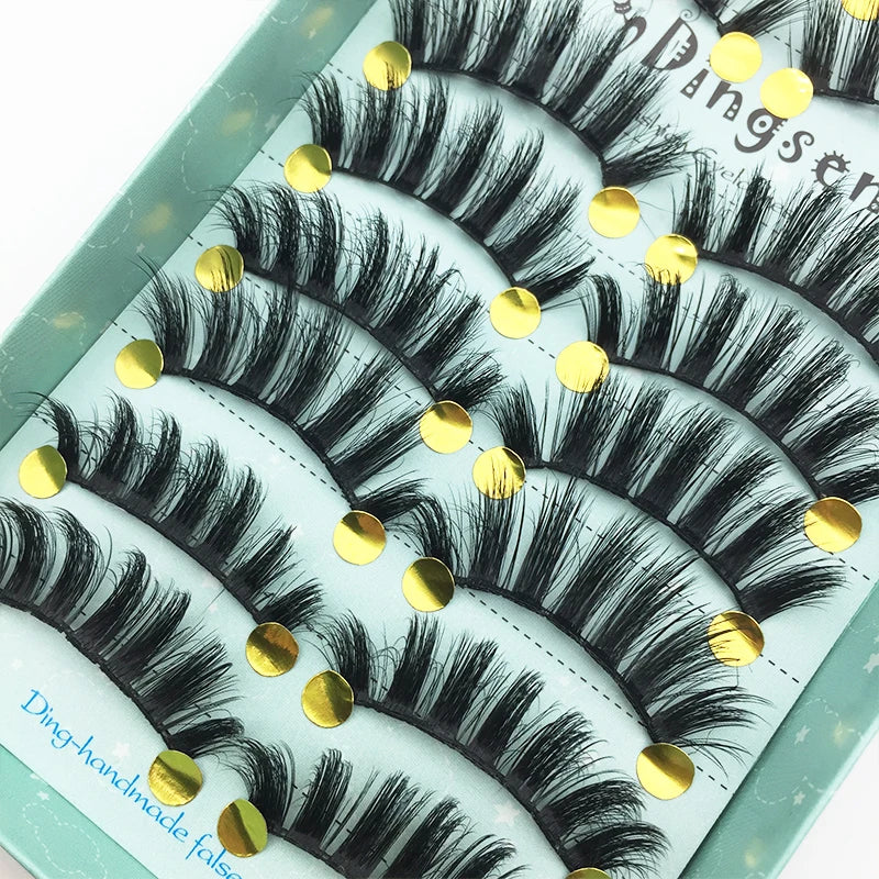 A display of black and gray mink false eyelashes arranged in rows on a light green surface.