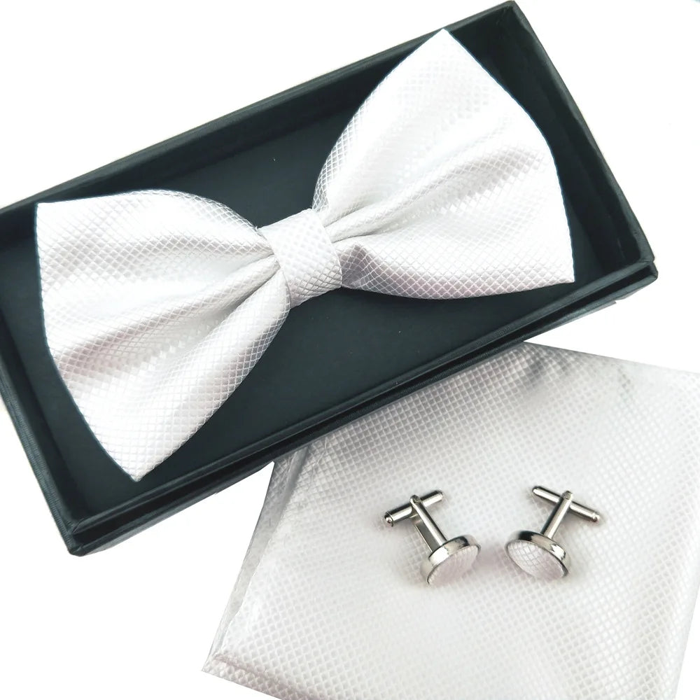 A white bow tie and cufflinks set displayed in a black box and a white pouch.
