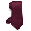 Cravate en soie jacquard marron, roulée et présentée sur fond blanc.