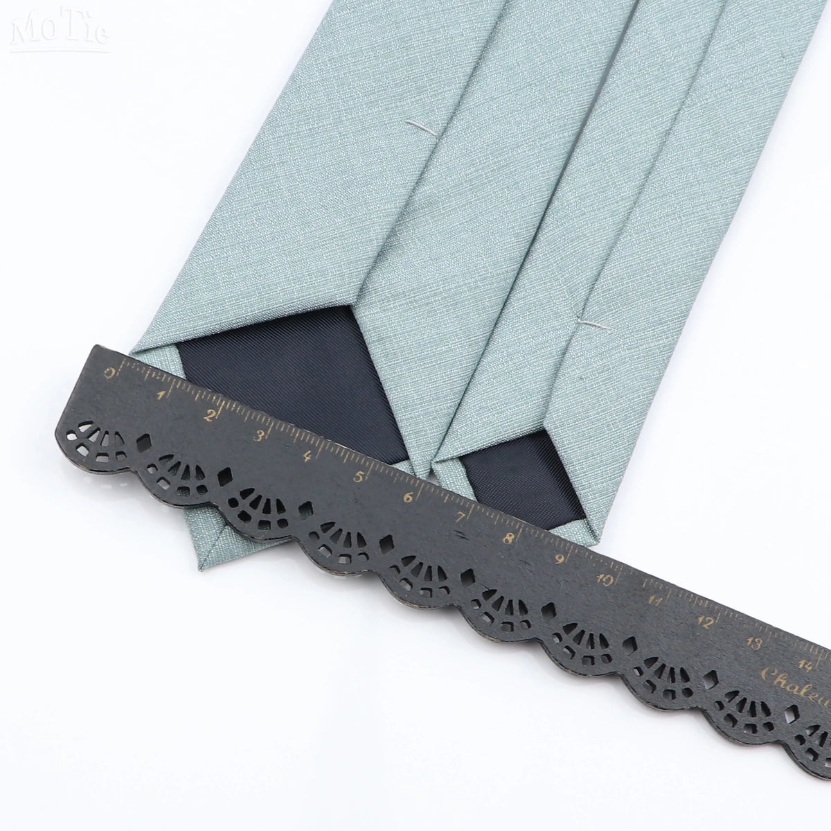 A close-up of a light blue bamboo fiber tie folded and displayed next to a measuring ruler.