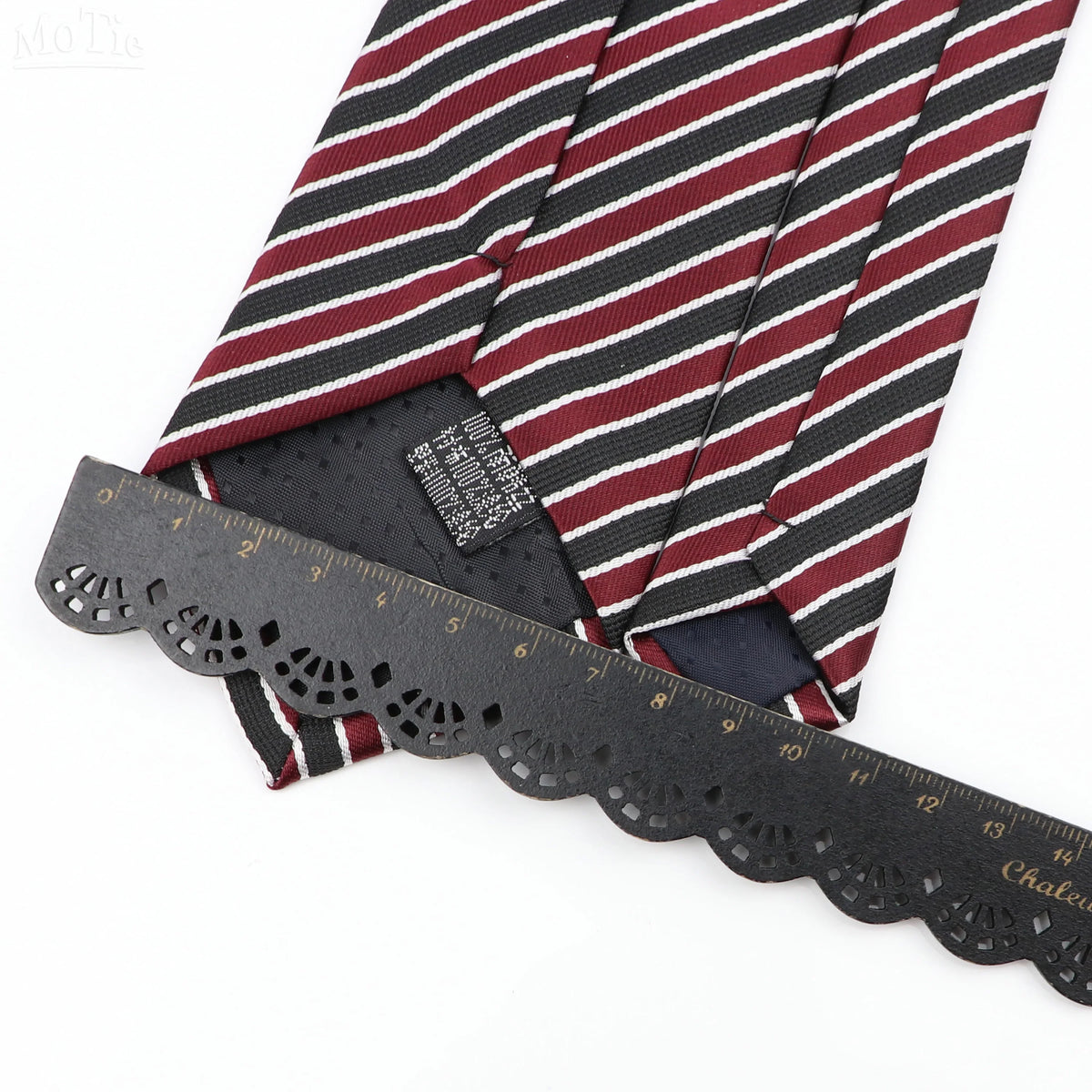 A close-up of a classic men's tie featuring a striped pattern with plaid dots and a black measuring tape.