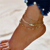 Gold heart chain anklets worn on a foot against a light background.