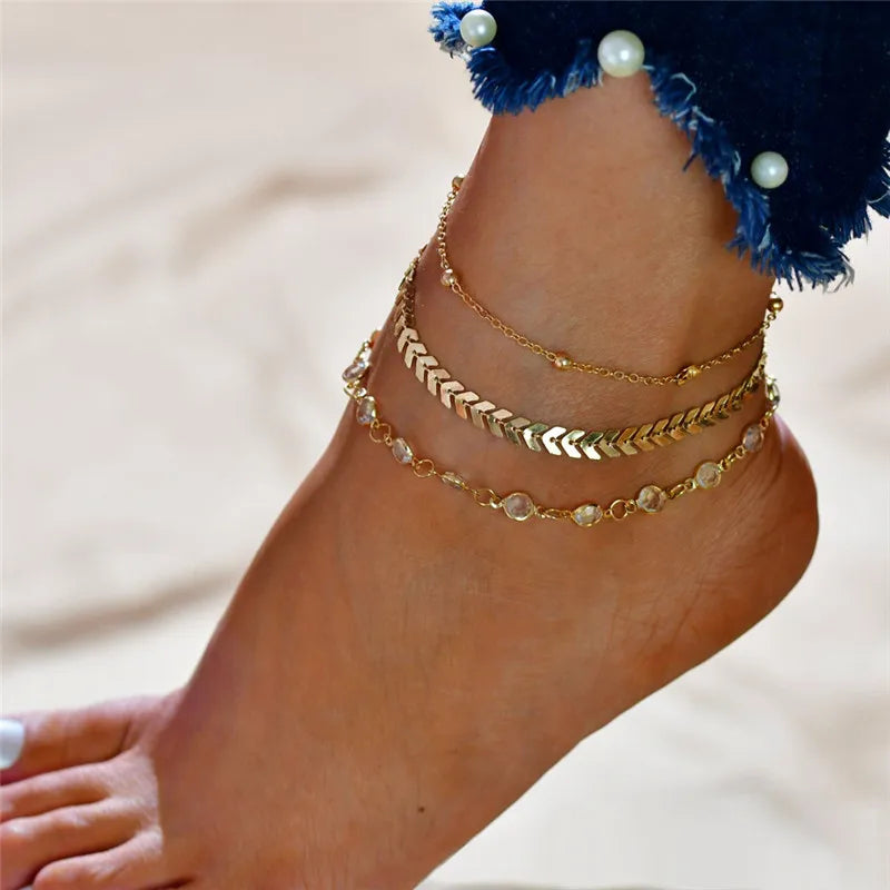 Gold heart chain anklets worn on a foot against a light background.