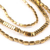 A close-up of gold-plated hematite round cube beads arranged in strands for DIY jewelry making.