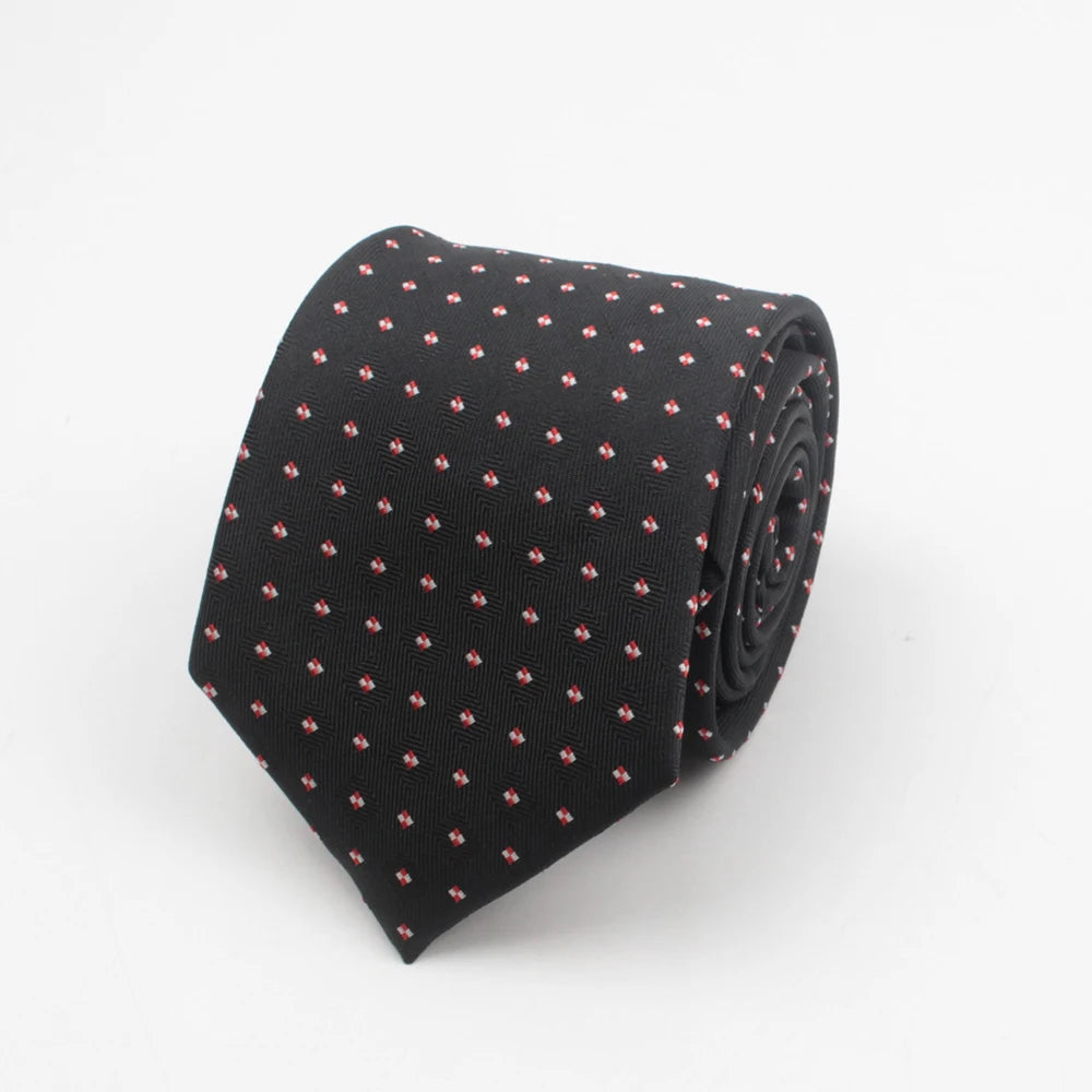 Black necktie with a small red dot pattern rolled up.