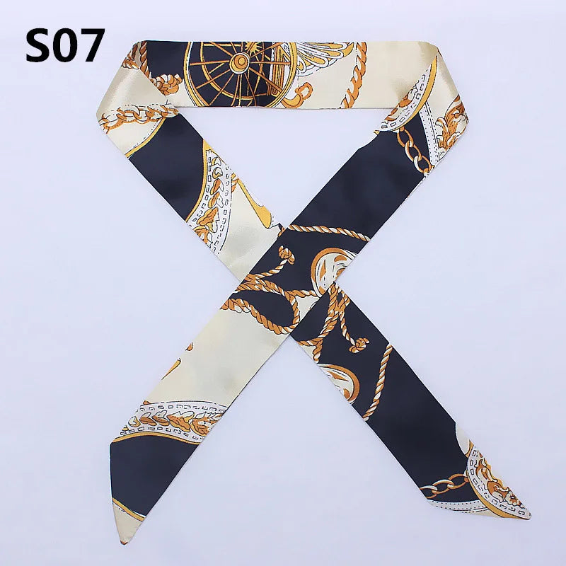 A black and cream silk scarf or headband featuring an ornate gold chain pattern.
