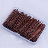 A clear plastic container filled with numerous thin, elegant copper-colored metal hair clips.