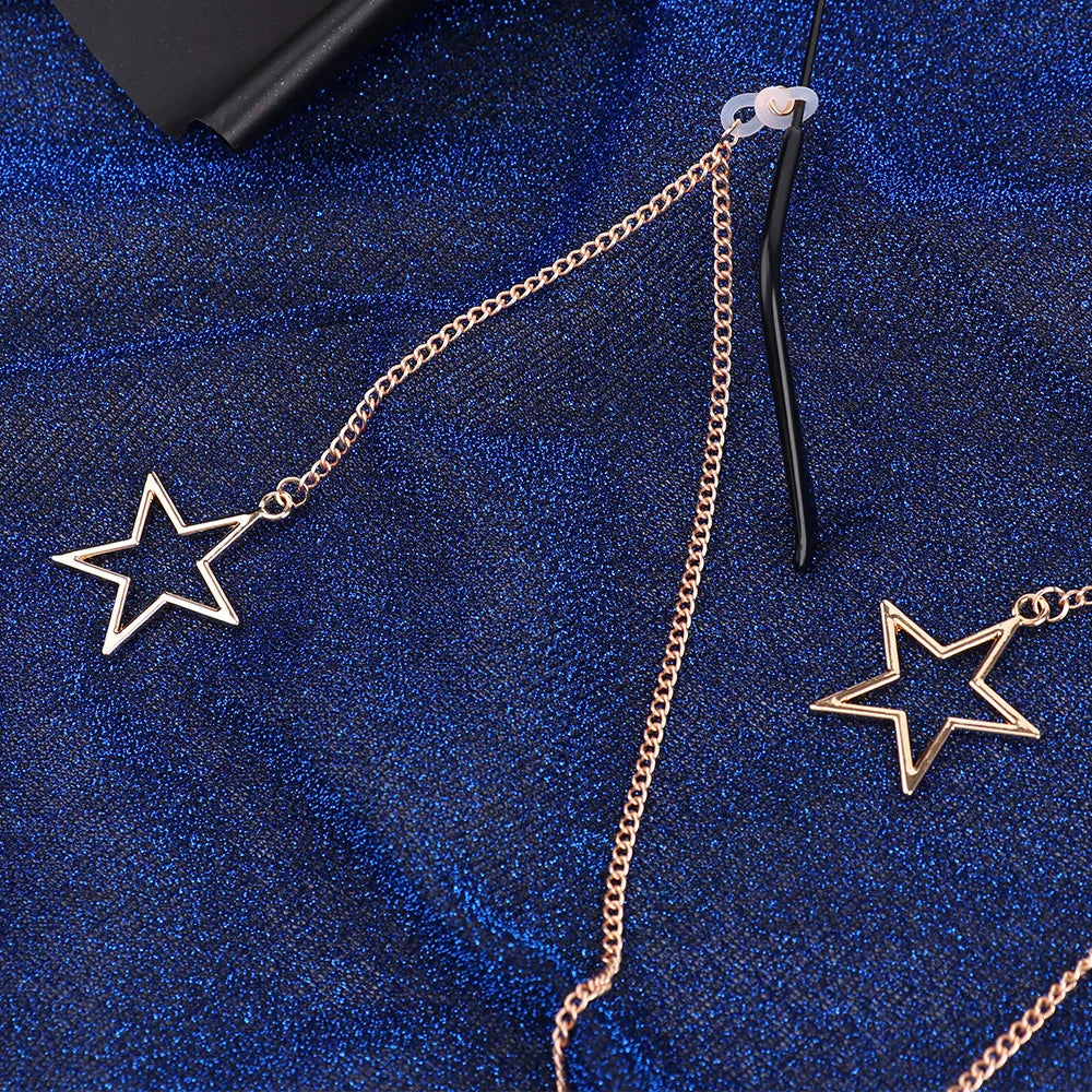 Gold-toned hollow star pendant on a chain against a dark blue textured fabric.