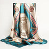 A luxurious satin silk scarf in teal and pink tones draped elegantly.