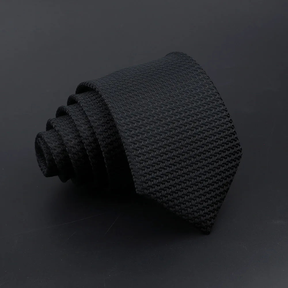 A black knitted tie with plaid dots shown in a close-up view.