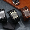 A close-up of a retro leather pirate compass bracelet for men resting on a dark surface.