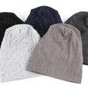 A collection of four knit beanie hats in black, navy blue, light gray, and charcoal gray with scattered rhinestones.