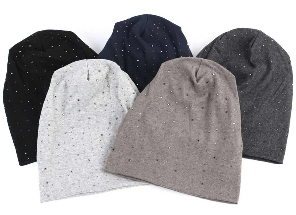 A collection of four knit beanie hats in black, navy blue, light gray, and charcoal gray with scattered rhinestones.
