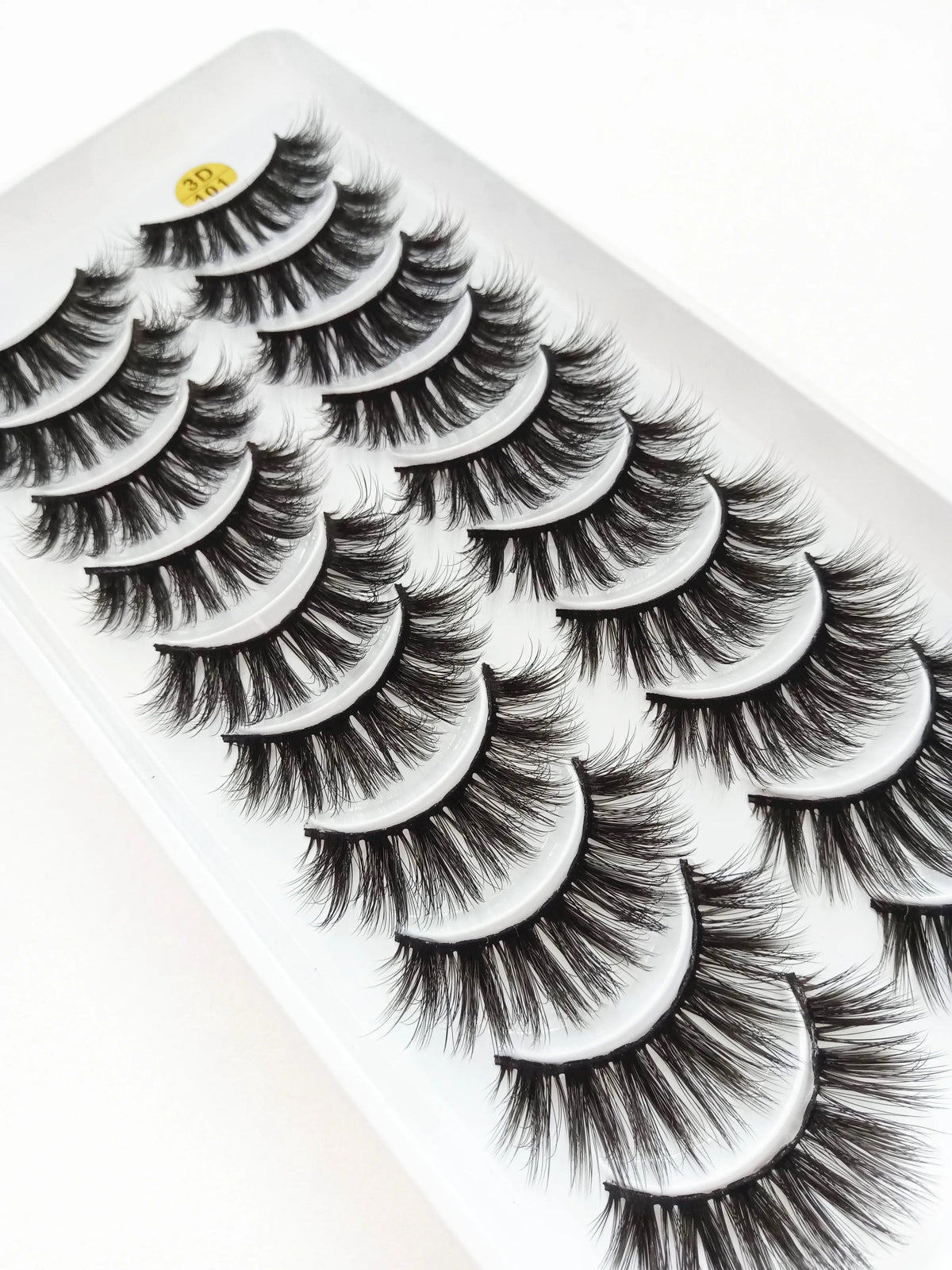 A close-up of dramatic mink false eyelashes applied to an eye, showcasing long, voluminous lashes.