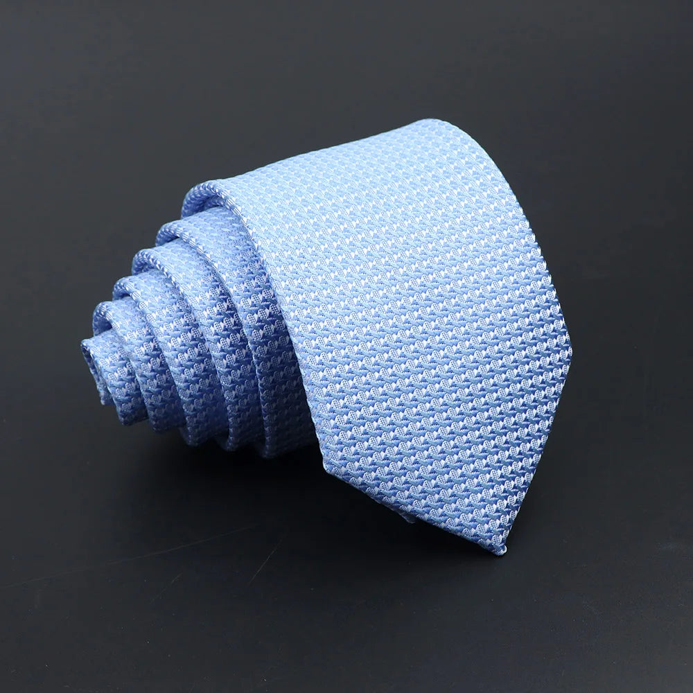 A light blue classic men's tie with a textured pattern is rolled into a spiral shape.