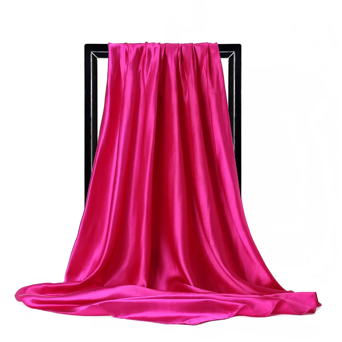 Una vibrante bufanda de seda satinada rosa drapeada en un soporte negro.