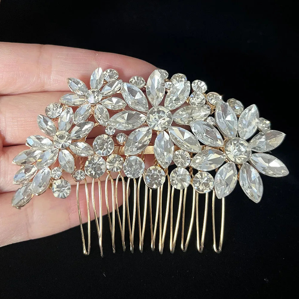 A bridal hair comb tiara featuring silver rhinestones and floral designs, held in a hand.