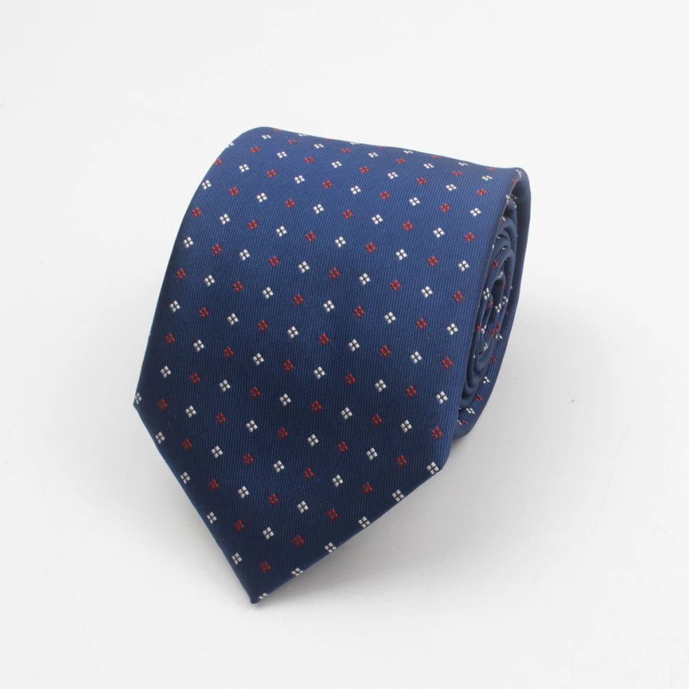 A dark blue necktie with a repeating pattern of small red dots and squares.