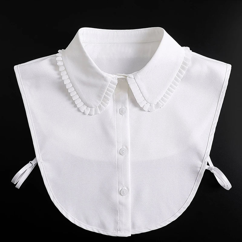 White blouse with a false collar and detachable neckline shown against a black background.