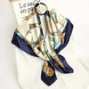 A luxury satin silk scarf featuring an ornate gold and blue pattern tied around a white shirt.