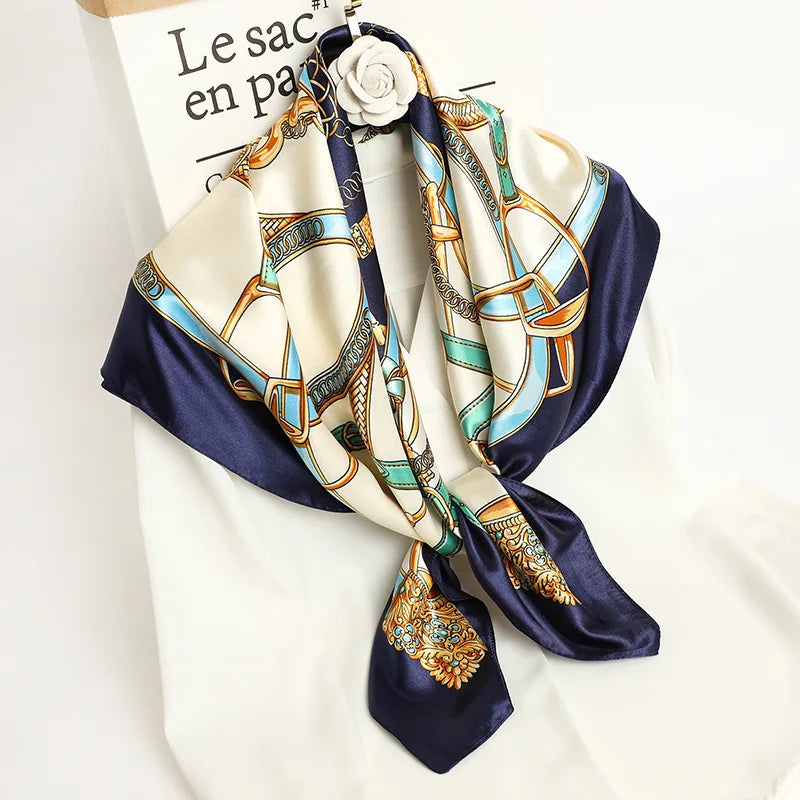 A luxury satin silk scarf featuring an ornate gold and blue pattern tied around a white shirt.