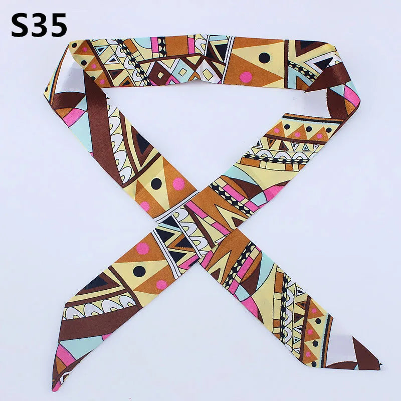 A multi-color leopard print silk headband scarf with geometric patterns in brown, pink, and beige tones.