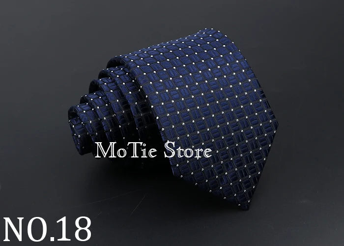 A dark blue patterned necktie with small light dots, shown rolled and draped.