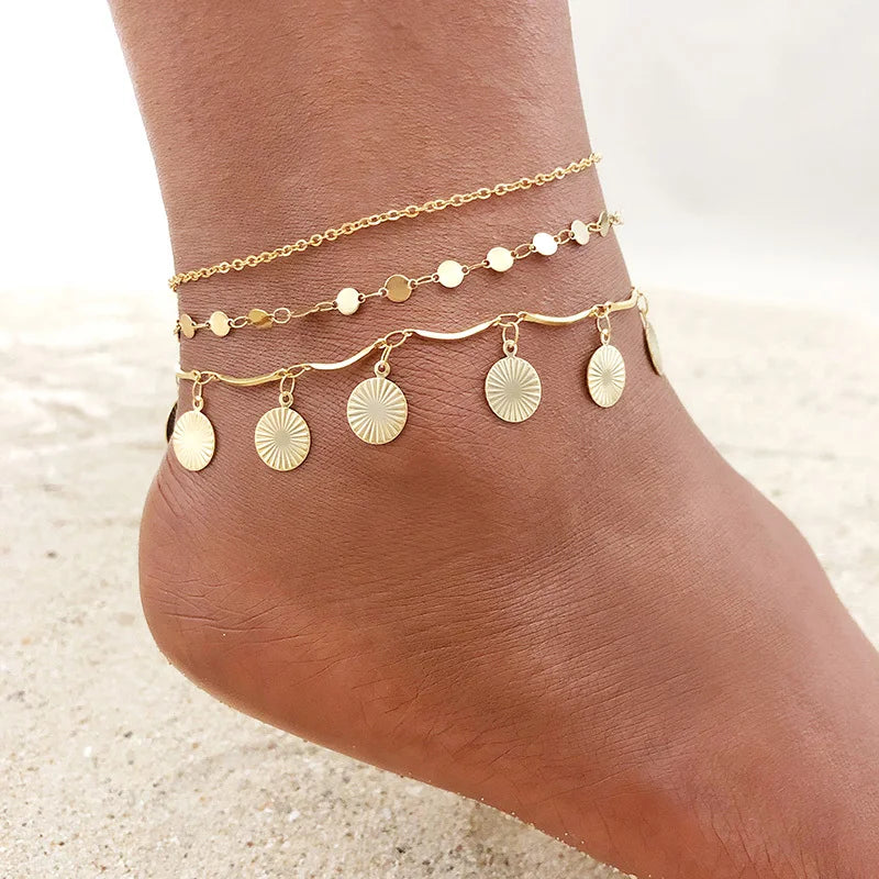 Gold stainless steel anklets layered on a woman's ankle.