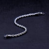 A silver stainless steel twisted rope chain bracelet lying on a dark surface.