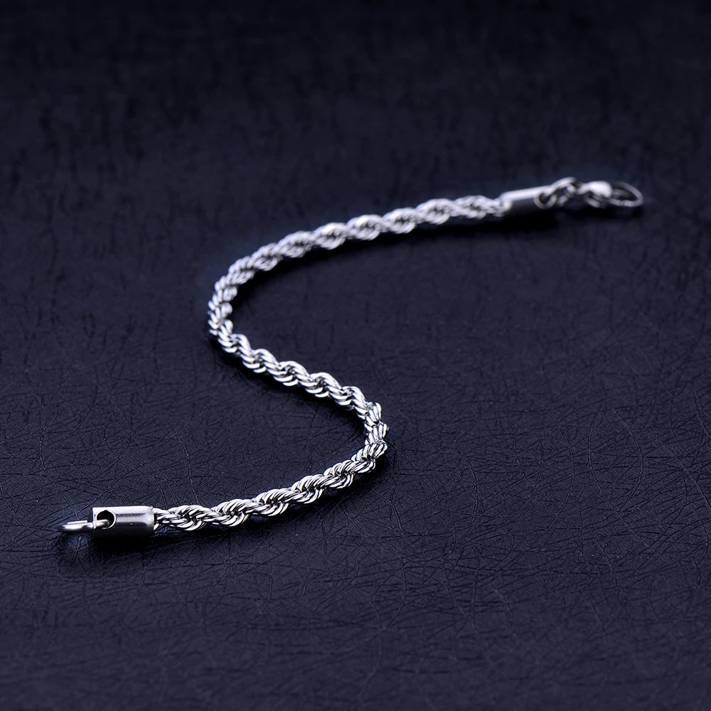 A silver stainless steel twisted rope chain bracelet lying on a dark surface.