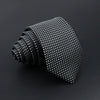 A black classic men's tie with a subtle plaid dot pattern, rolled and displayed on a dark surface.
