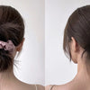 A close-up of a woman's hair styled in a low bun with pink silk scrunchies.